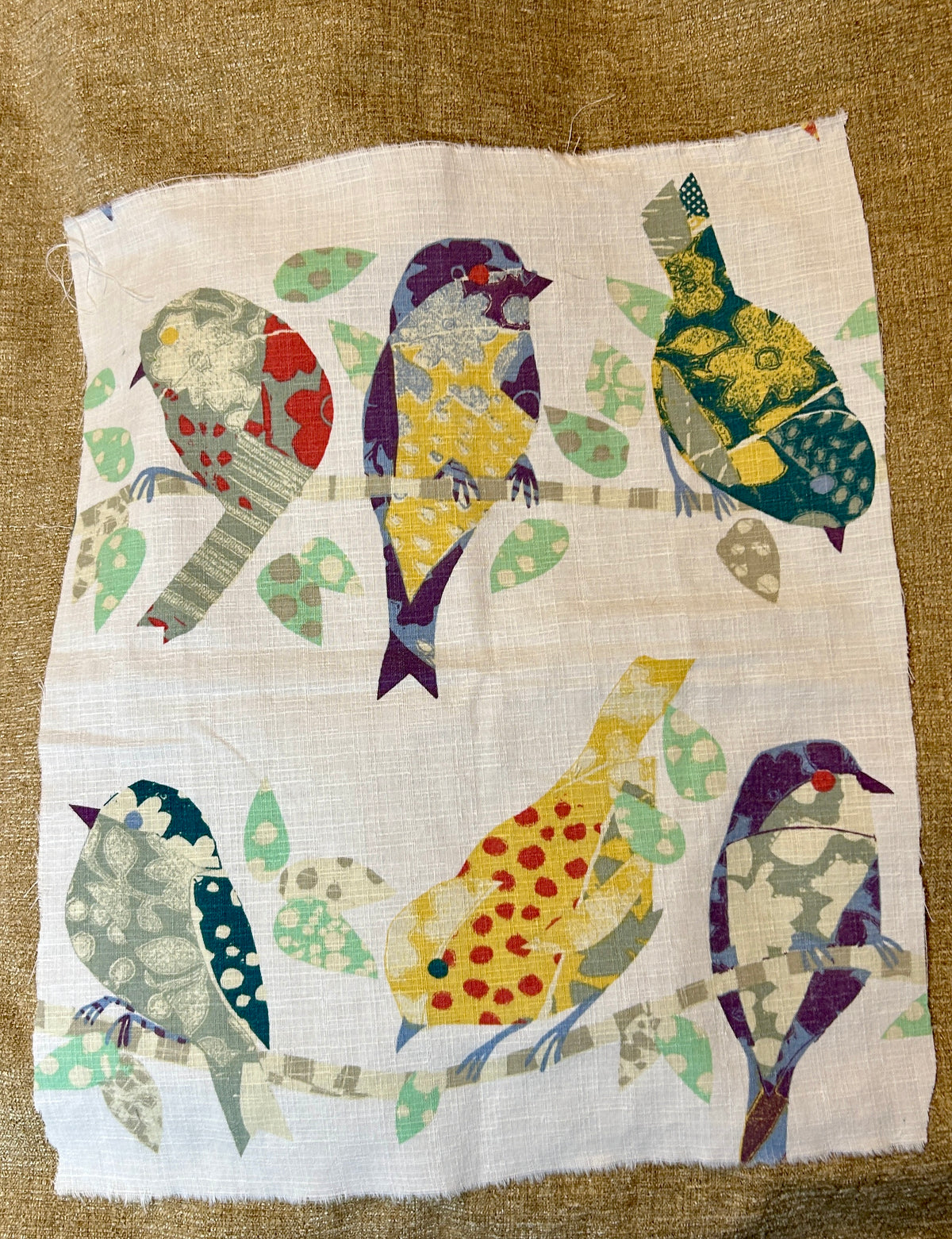 Patchwork fabric with colorful bird patterns on a brown background